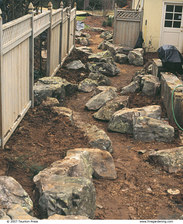 During construction, a streambed was created to direct water flow through the back, side, and front yards toward a street drain