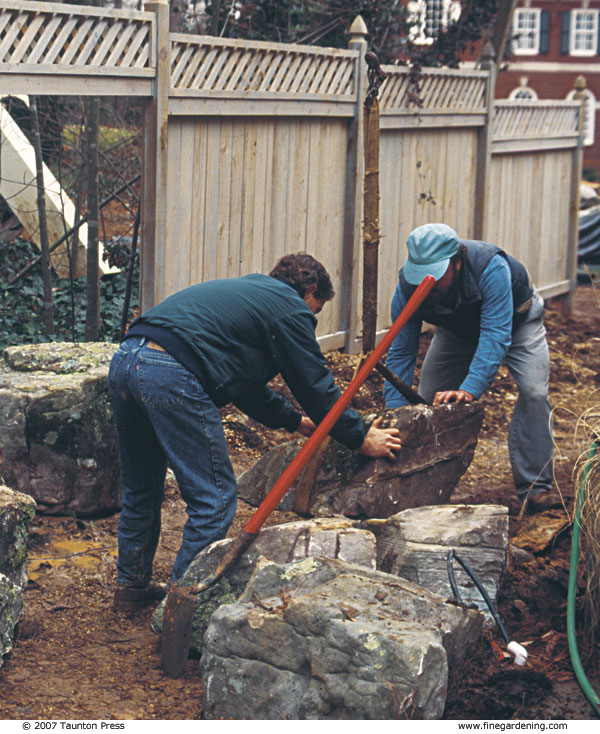 Boulders are placed one at a time to create the streambank, then partially buried to create planting pockets and a natural look.