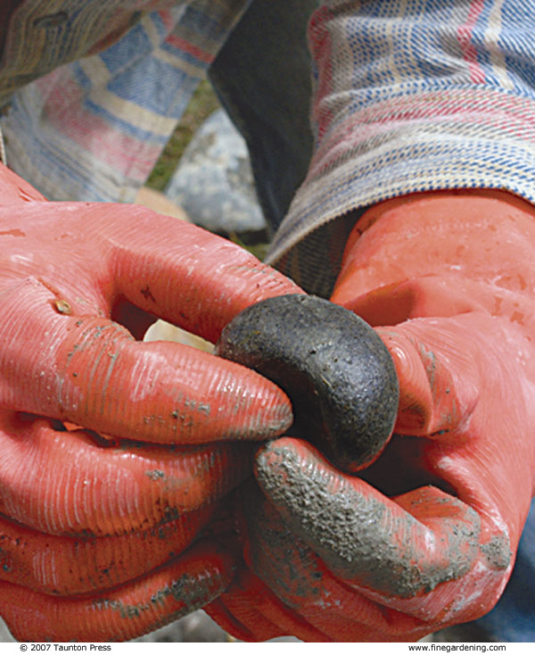 close-up of gloved hands holding a smooth rock.