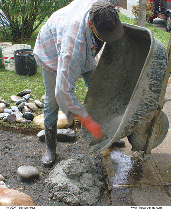 Author emptying mortar from wheelbarrow onto walkway.