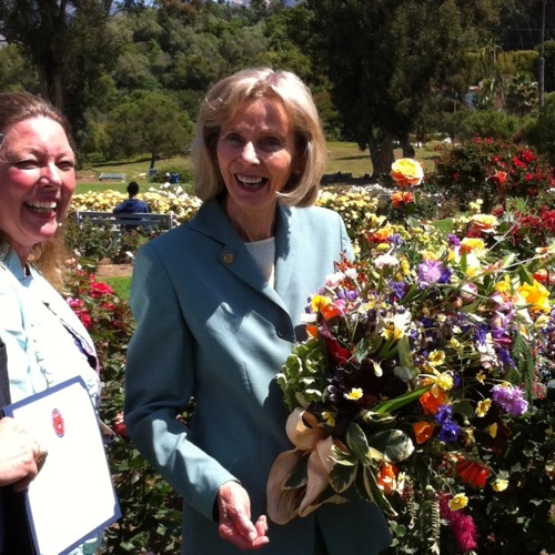 Congresswoman Lois Capps with bouquet from flowers at each tour stop. Molly Barker, exec director of Casa del Herrero, left.
