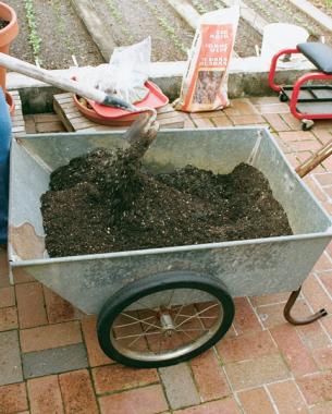 mixing nutrients and soil in a wheelbarrow